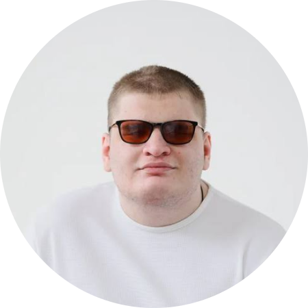 Мужчина с короткими русыми волосами в белом свитере и темных очках.